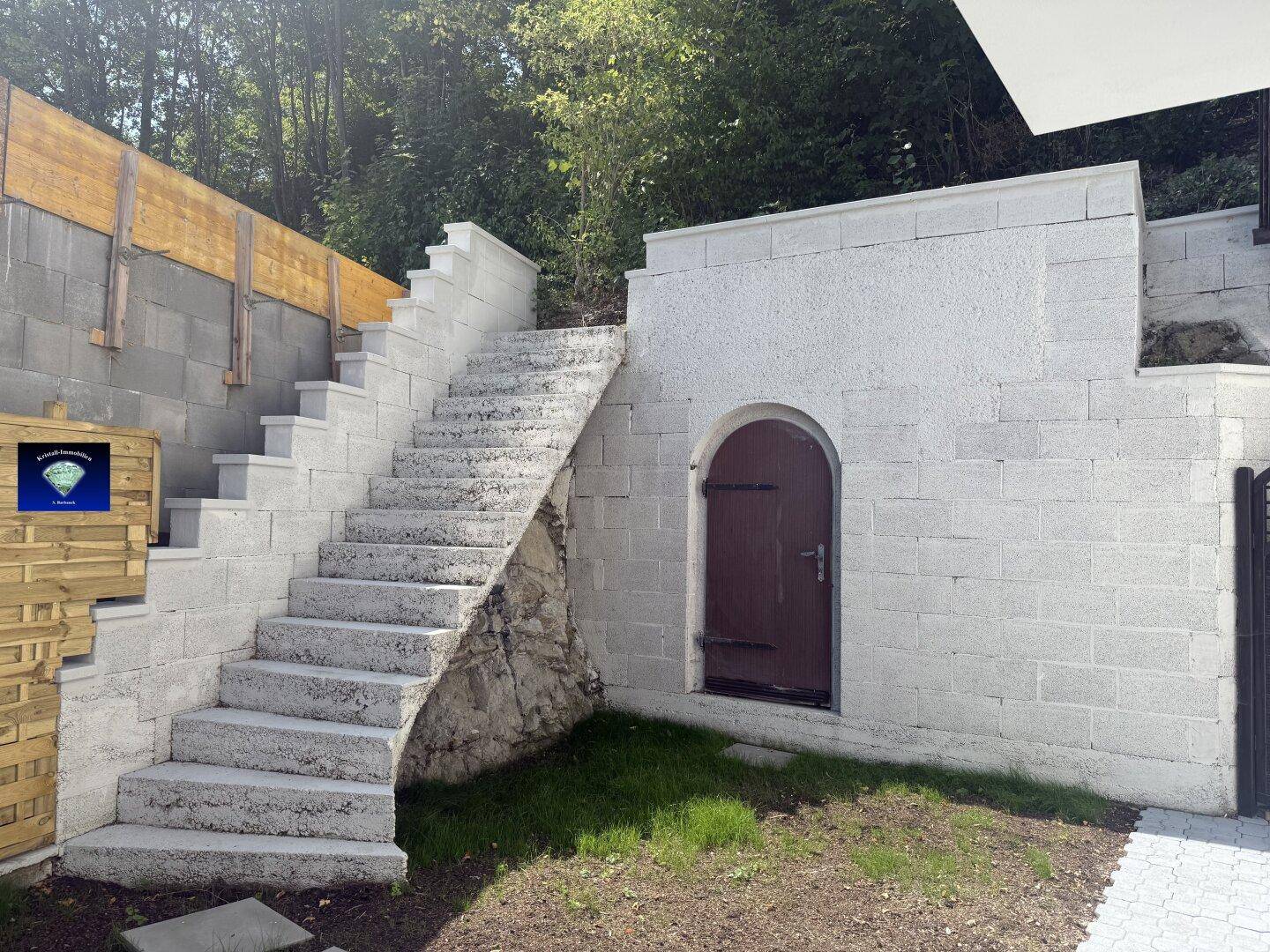 Steintreppe führt zu einem höher gelegenen Bereich mit einer rustikalen Kellertür.