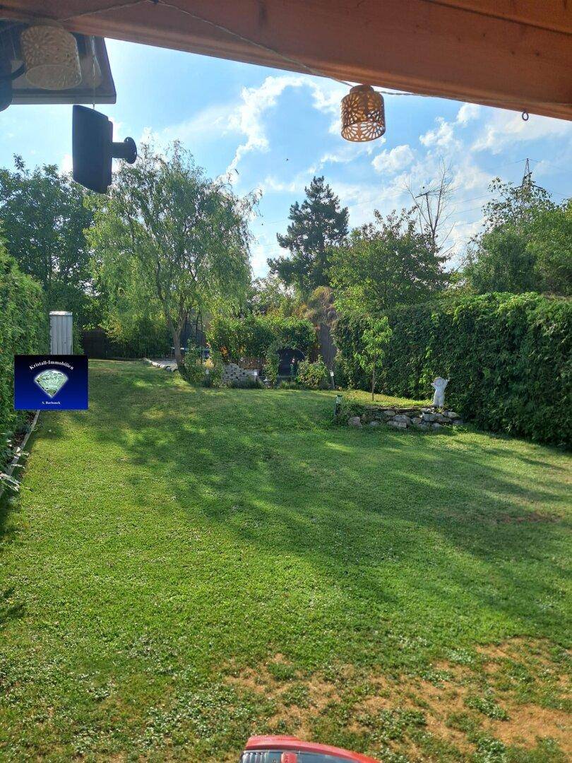 Weitläufiger Garten mit Rasenfläche, Bäumen und viel Grün.