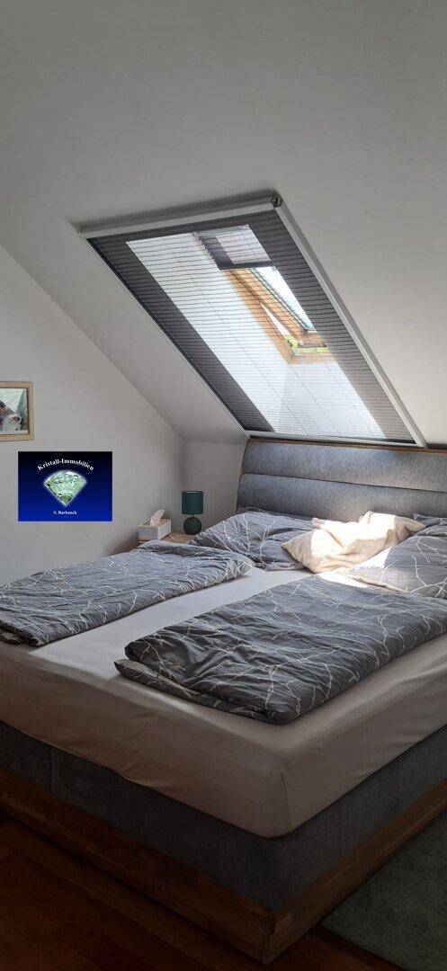 Gemütliches Schlafzimmer im Dachgeschoss mit großem Bett und Dachfenster.