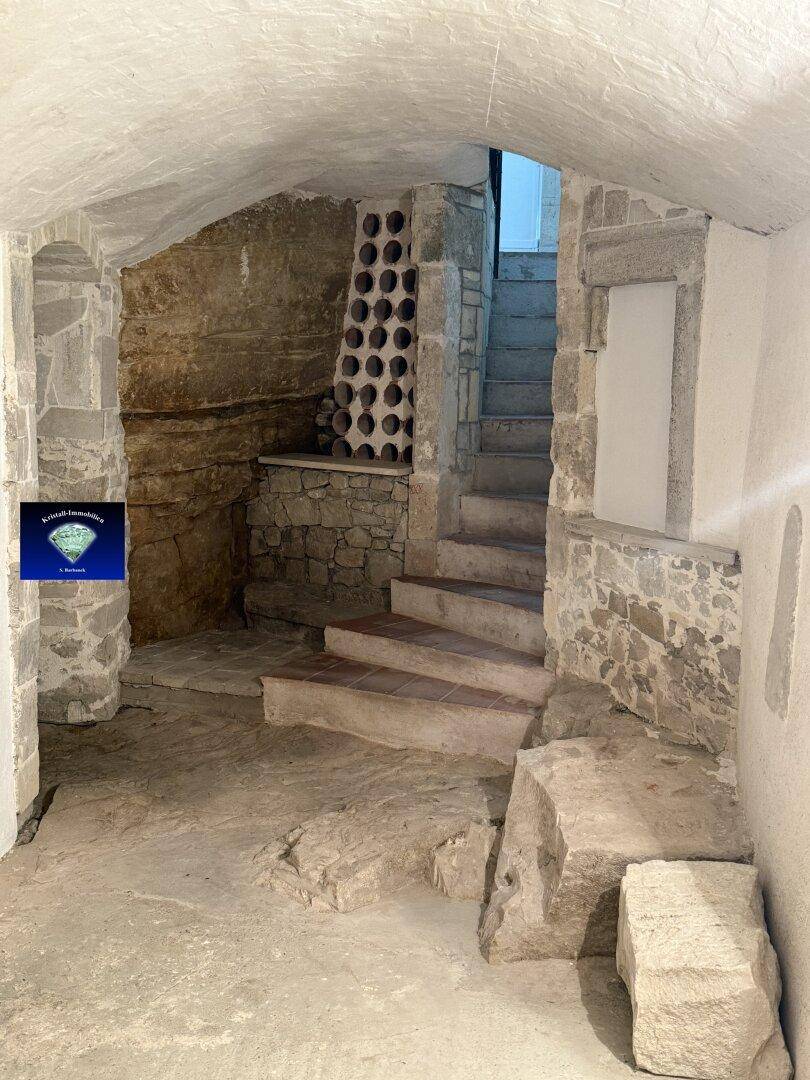 Historischer Weinkeller mit Steinmauern, Steintreppe und integriertem Weinregal, ideal für Lagerung.