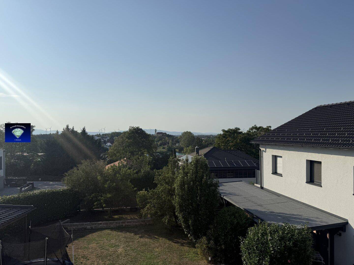Rückansicht des Hauses mit Flachdach-Anbau und weitem Blick in die Ferne.