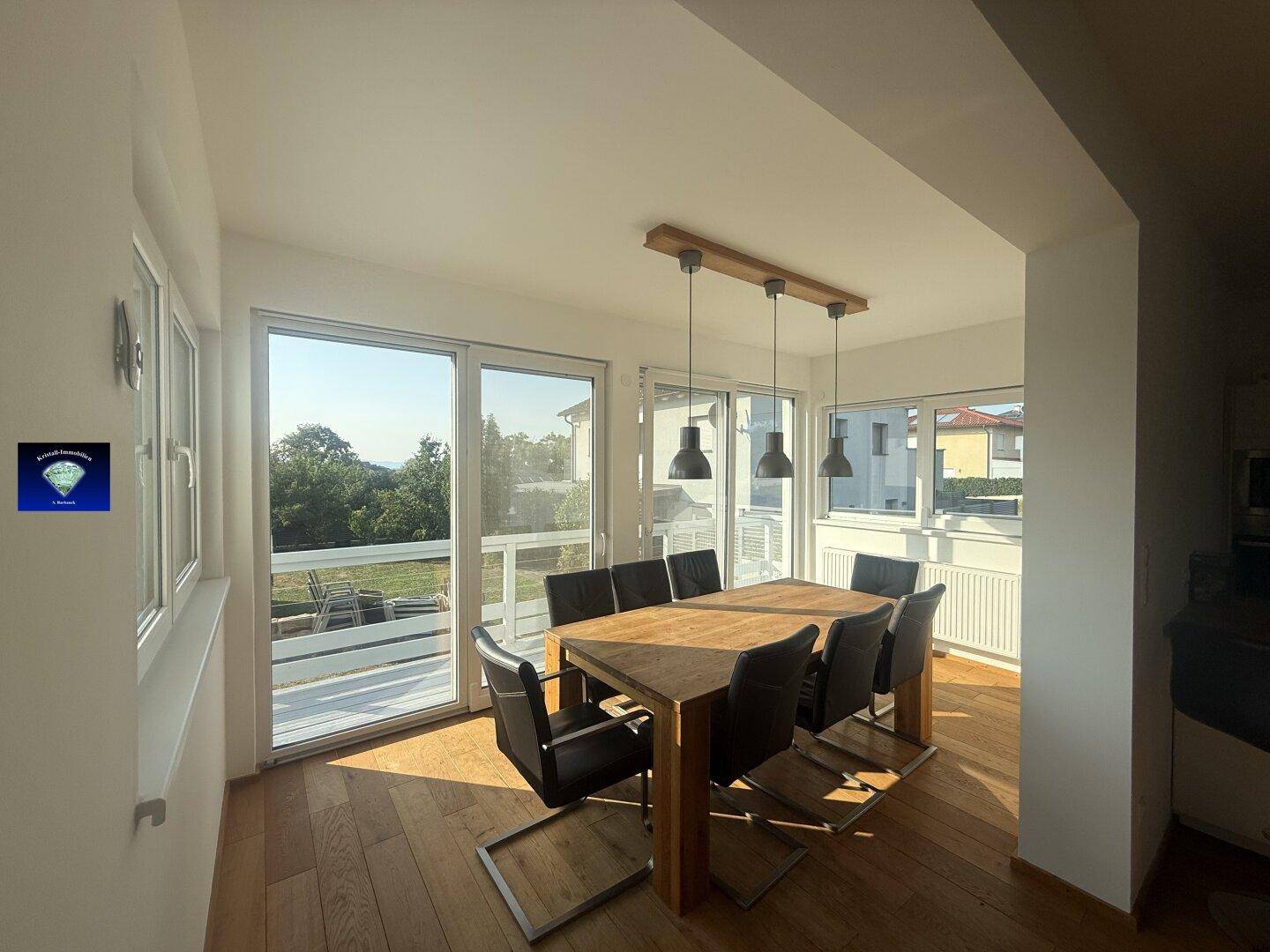 Heller Essbereich mit Holztisch und Stühlen, großen Fenstern und Zugang zum Garten.