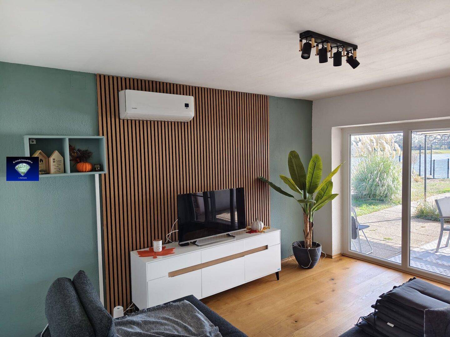 Modernes Wohnzimmer mit Holzboden, dekorativer Wandverkleidung, Klimaanlage und Seeblick.
