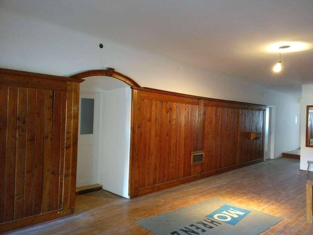 Großer Raum mit umfangreicher Holzvertäfelung an den Wänden und einem Holzboden.