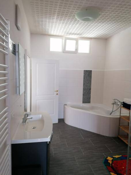 Geräumiges Badezimmer mit Waschbecken, Eckbadewanne und beheiztem Handtuchhalter.