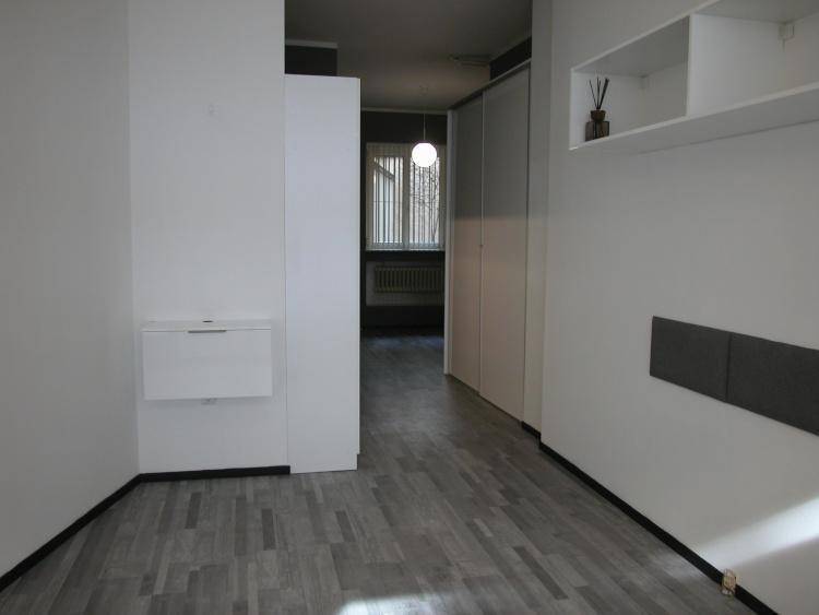 Leerer Innenraum mit hellen Wänden, integrierten Schränken und grauem Holzplankenboden.