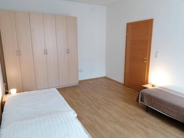 Geräumiges Schlafzimmer mit zwei Einzelbetten, großem Kleiderschrank und Holztür.