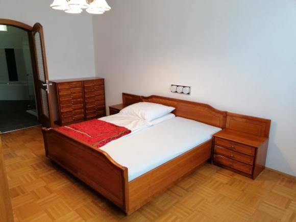Schlafzimmer mit klassischem Holzbett, Nachttischen und Kommode, bereit zur Einrichtung.