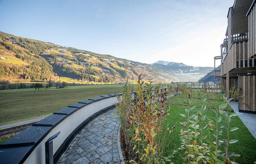 Gepflegte Außenanlage mit Rasen und Wegen, umgeben von einer malerischen Berglandschaft.