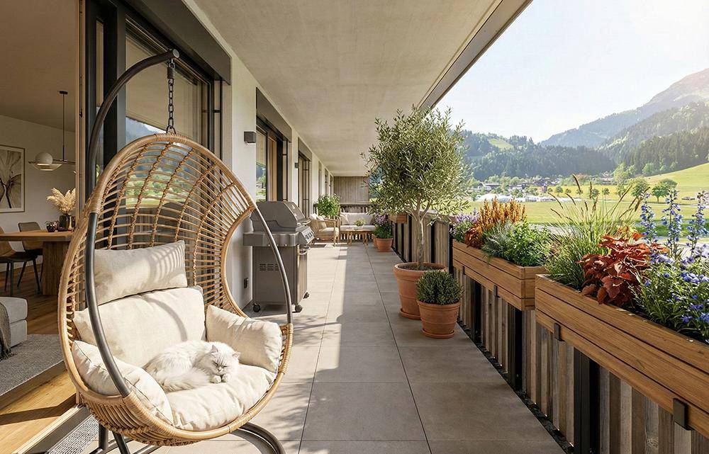Großer Balkon mit bequemen Sitzgelegenheiten, Pflanzen und weitem Blick auf die grüne Berglandschaft.