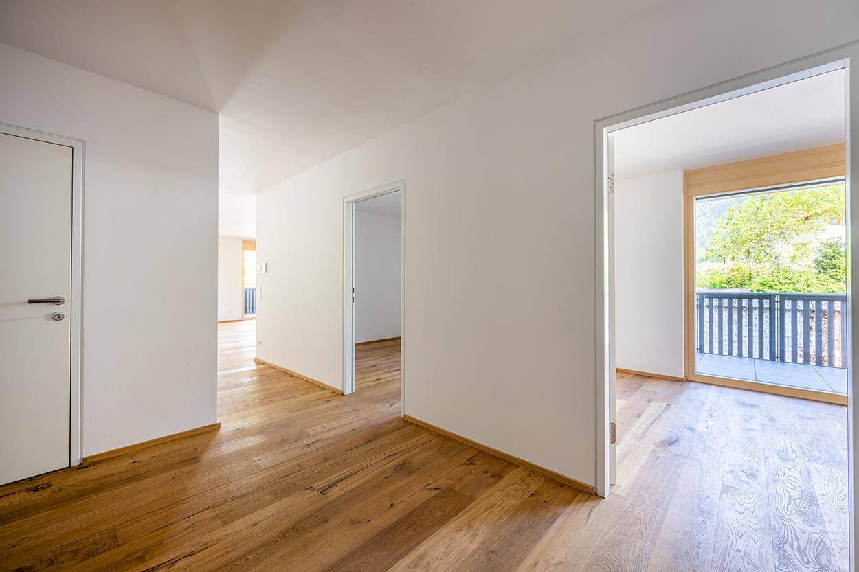 Heller Flur mit Eichenparkettboden und Zugang zu verschiedenen Räumen und einem Balkon.