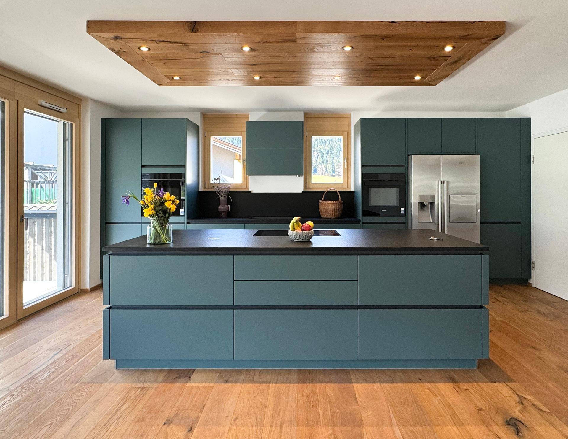 Moderne Küche mit dunkelblauen Schränken, Kücheninsel und Holzboden.