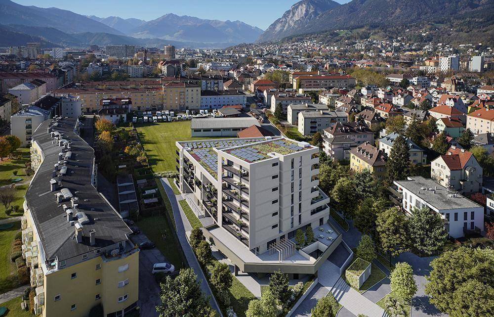 Weitläufige Luftaufnahme der Wohnanlage, eingebettet in eine städtische Landschaft mit Bergen im Hintergrund.