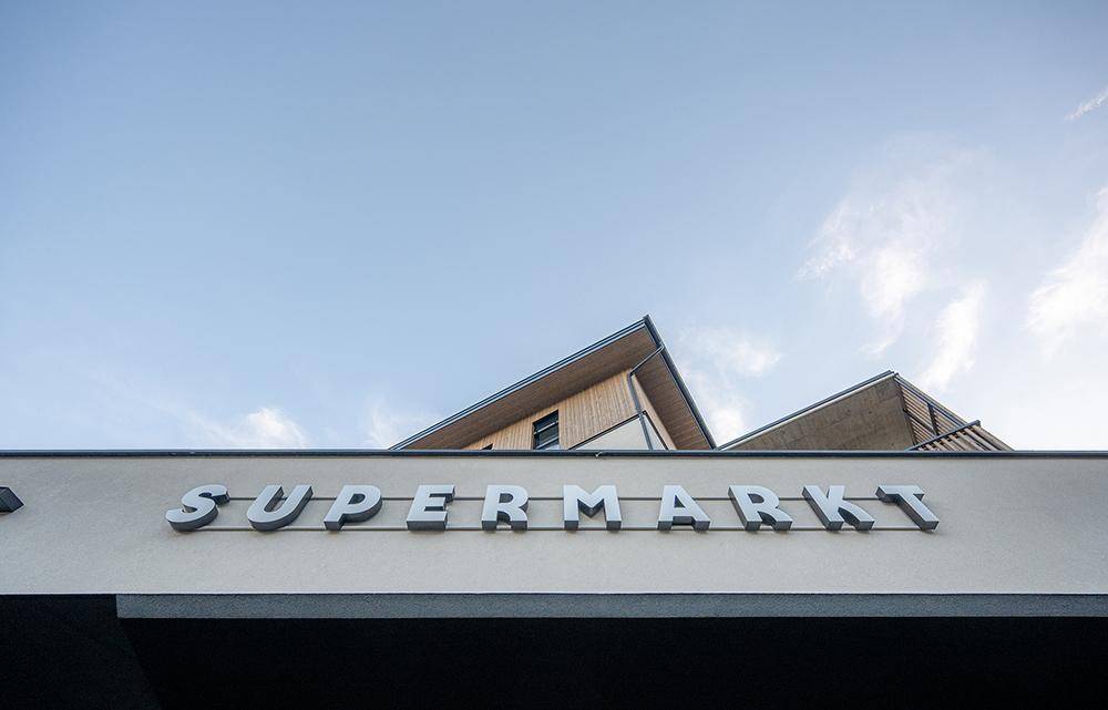 Detailansicht des Gebäudes mit dem Schriftzug "SUPERMARKT" unter blauem Himmel.