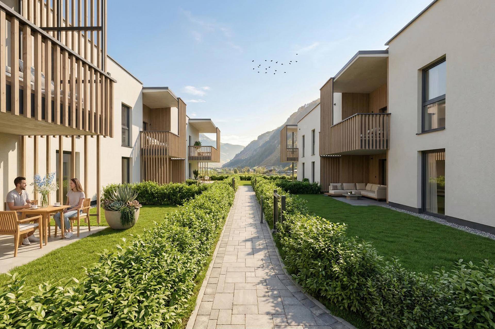 Gepflegte Gartenanlage mit Sitzbereich und Blick auf die umliegende Berglandschaft der modernen Wohnanlage.