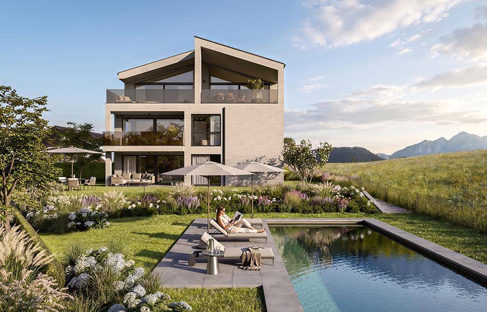 Moderne Wohnanlage mit Pool und Liegebereich, umgeben von grüner Landschaft und Bergen.