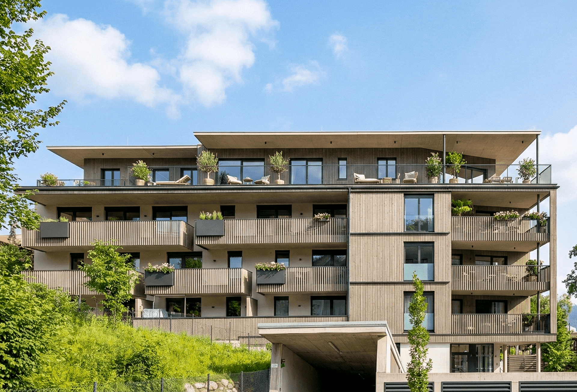 Moderne Wohnanlage mit Holzfassade, großzügigen Balkonen und Tiefgaragenzufahrt in grüner Umgebung.