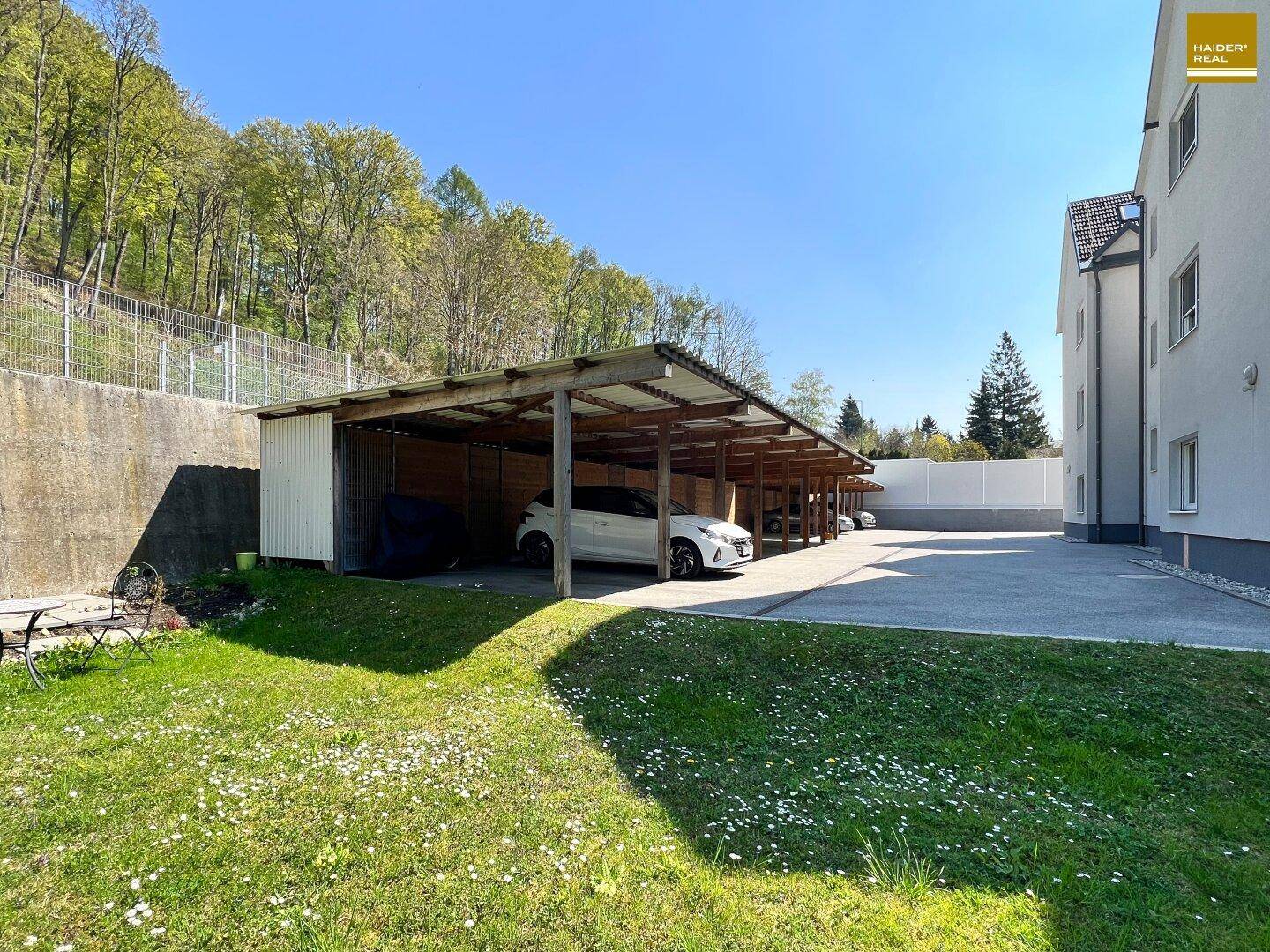 Blick auf Haus und Carports mit Abstellräumen dahinter