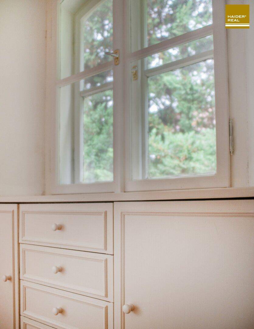 Detailansicht eines Fensters mit Blick auf Bäume und eines Teils der Einbauschränke.