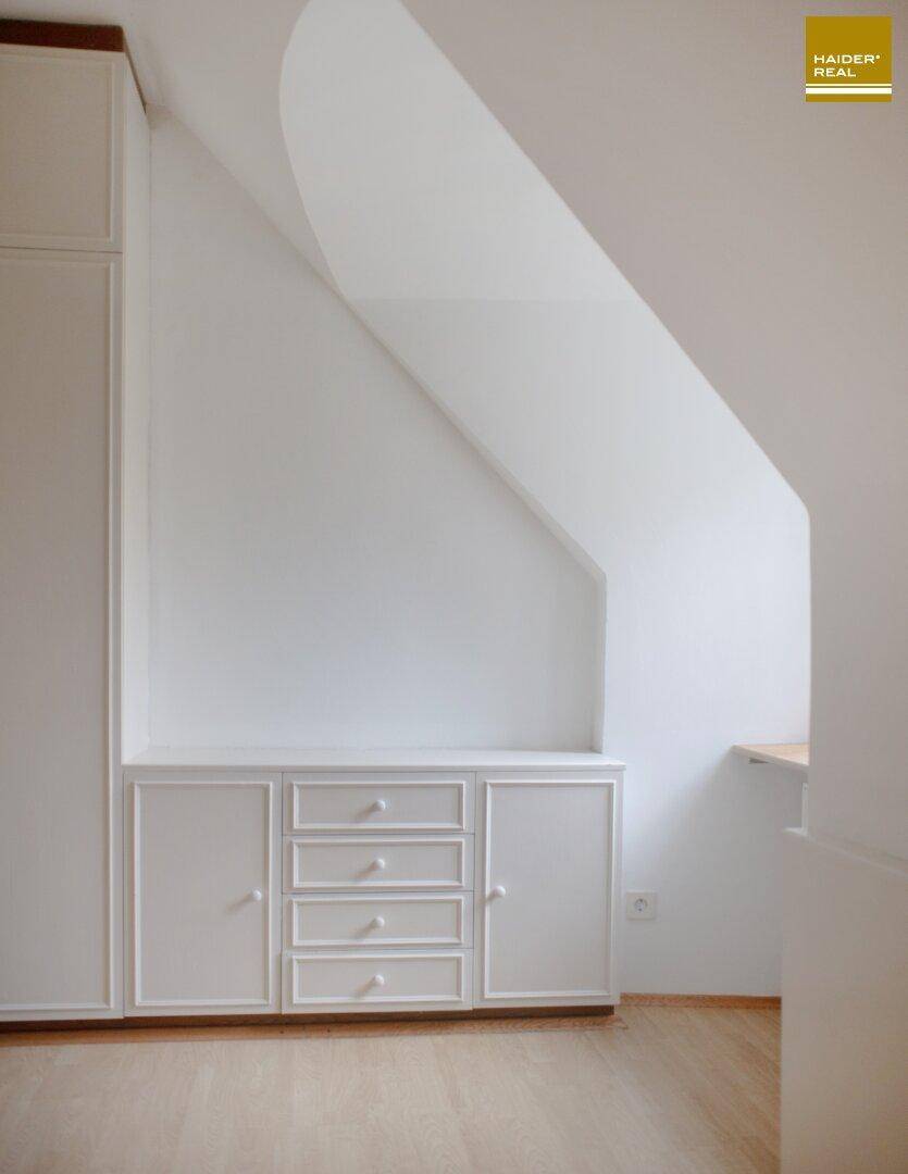 Dachgeschosszimmer mit schräger Decke und praktischen Einbauschränken für Stauraum.
