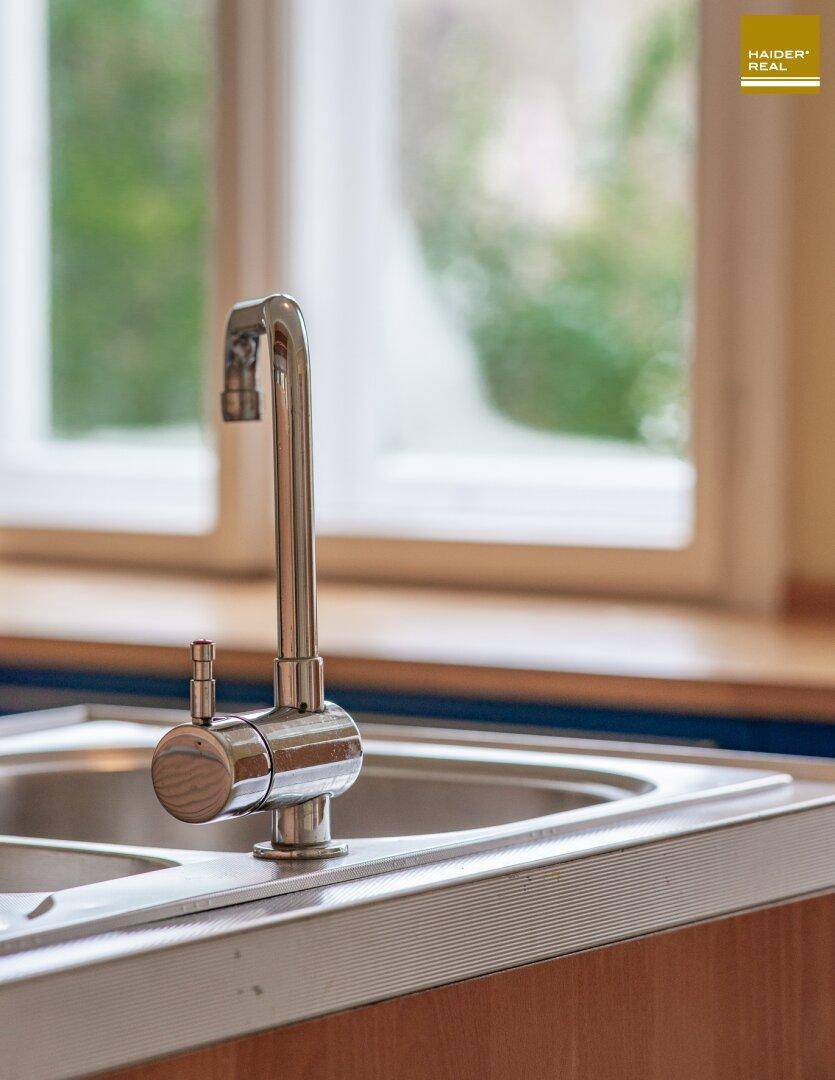 Küchenspüle mit modernem Wasserhahn und Fenster im Hintergrund.