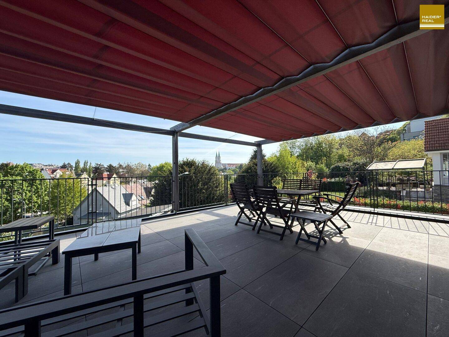 Geräumige Dachterrasse mit Sonnenschutz, Sitzgelegenheiten und weitem Blick über die Stadt.
