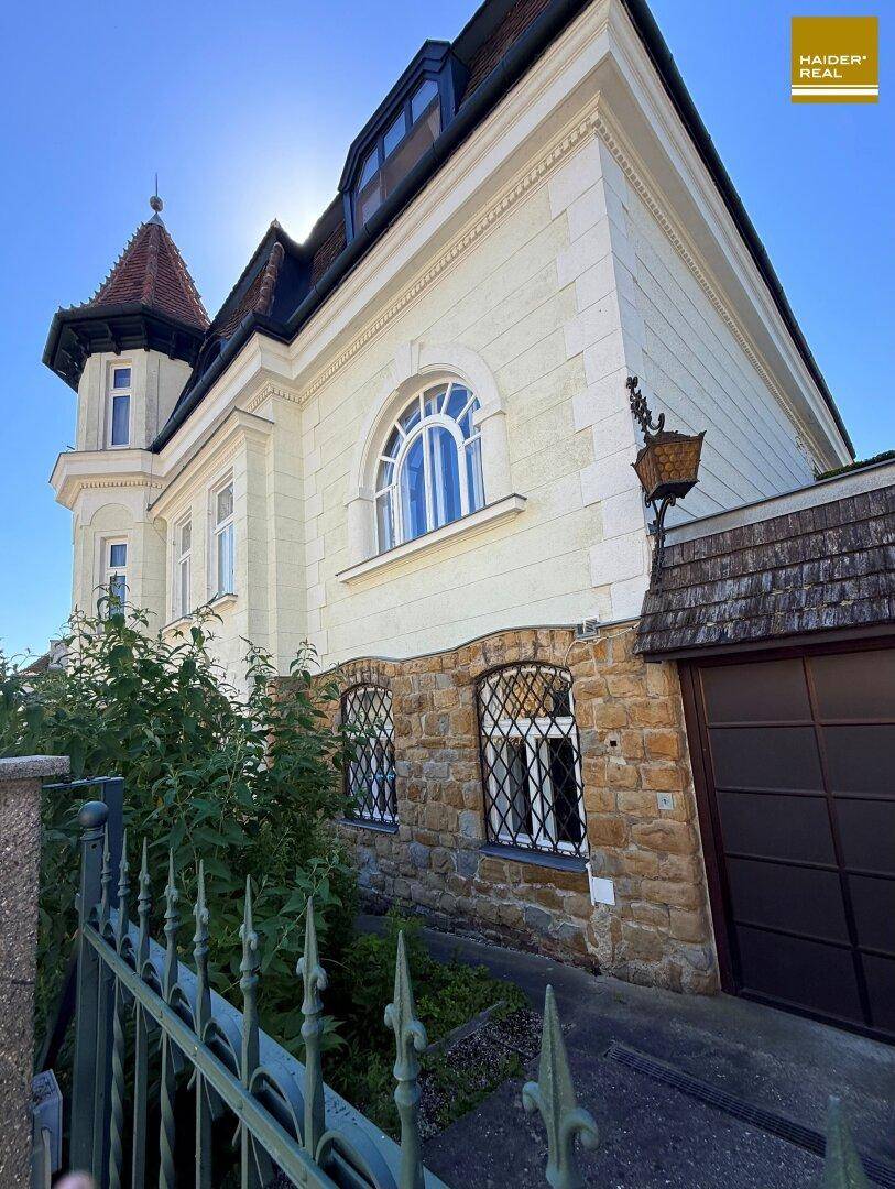 Seitenansicht der Villa mit Steinsockel, Rundbogenfenstern und integrierter Garage.