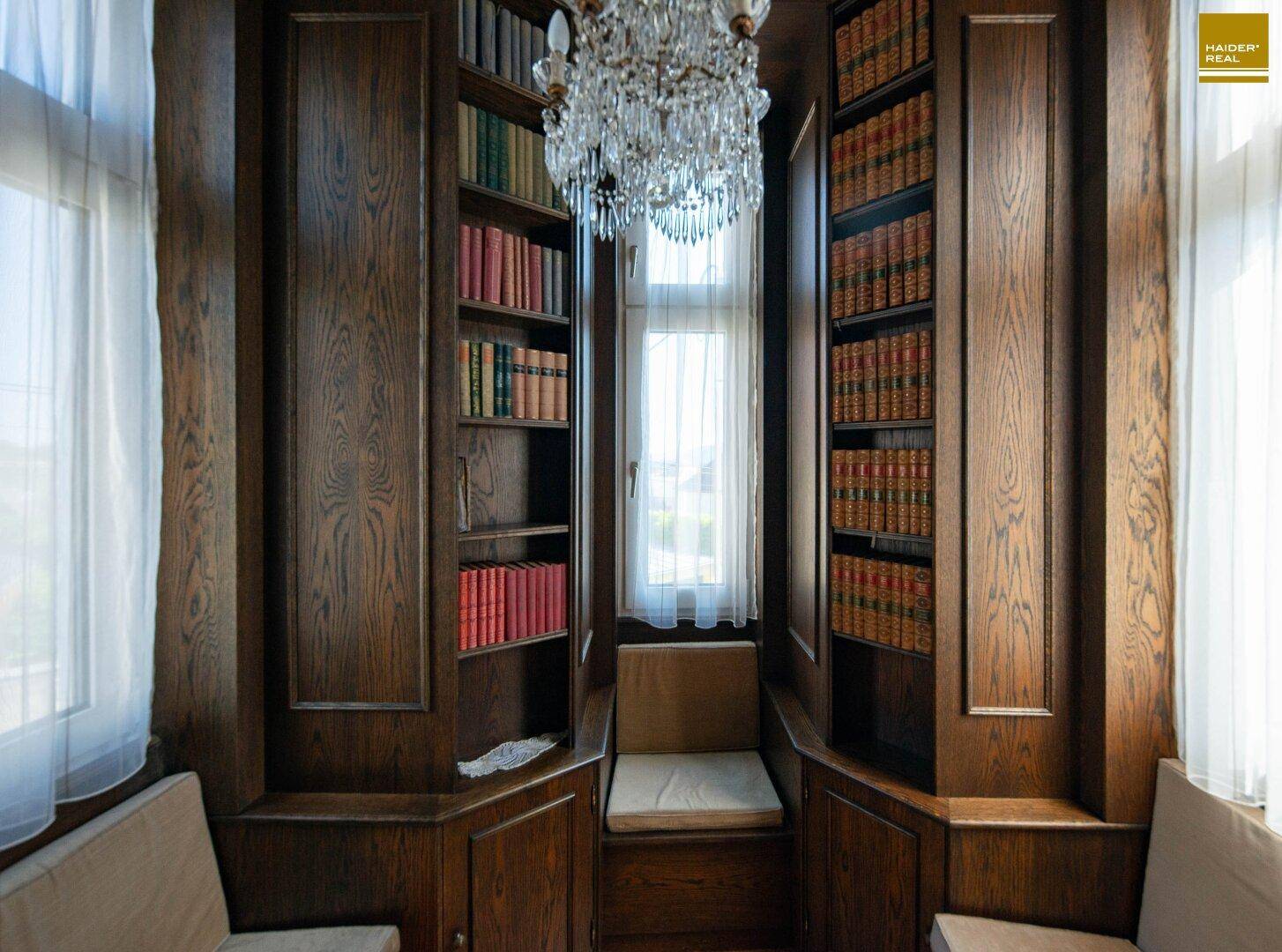 Gemütliche Bibliotheksecke mit eingebauten Holzregalen, Büchern und Kronleuchter.