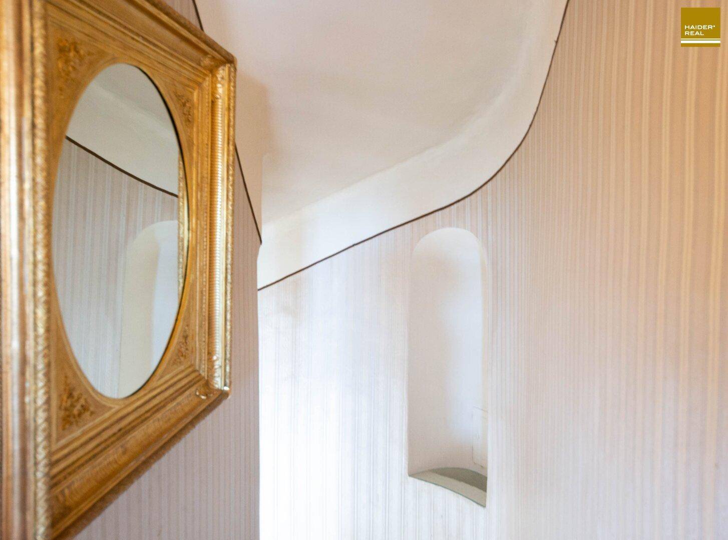 Detailansicht einer Wand mit eleganter Tapete und dekorativen Nischen im Flurbereich.