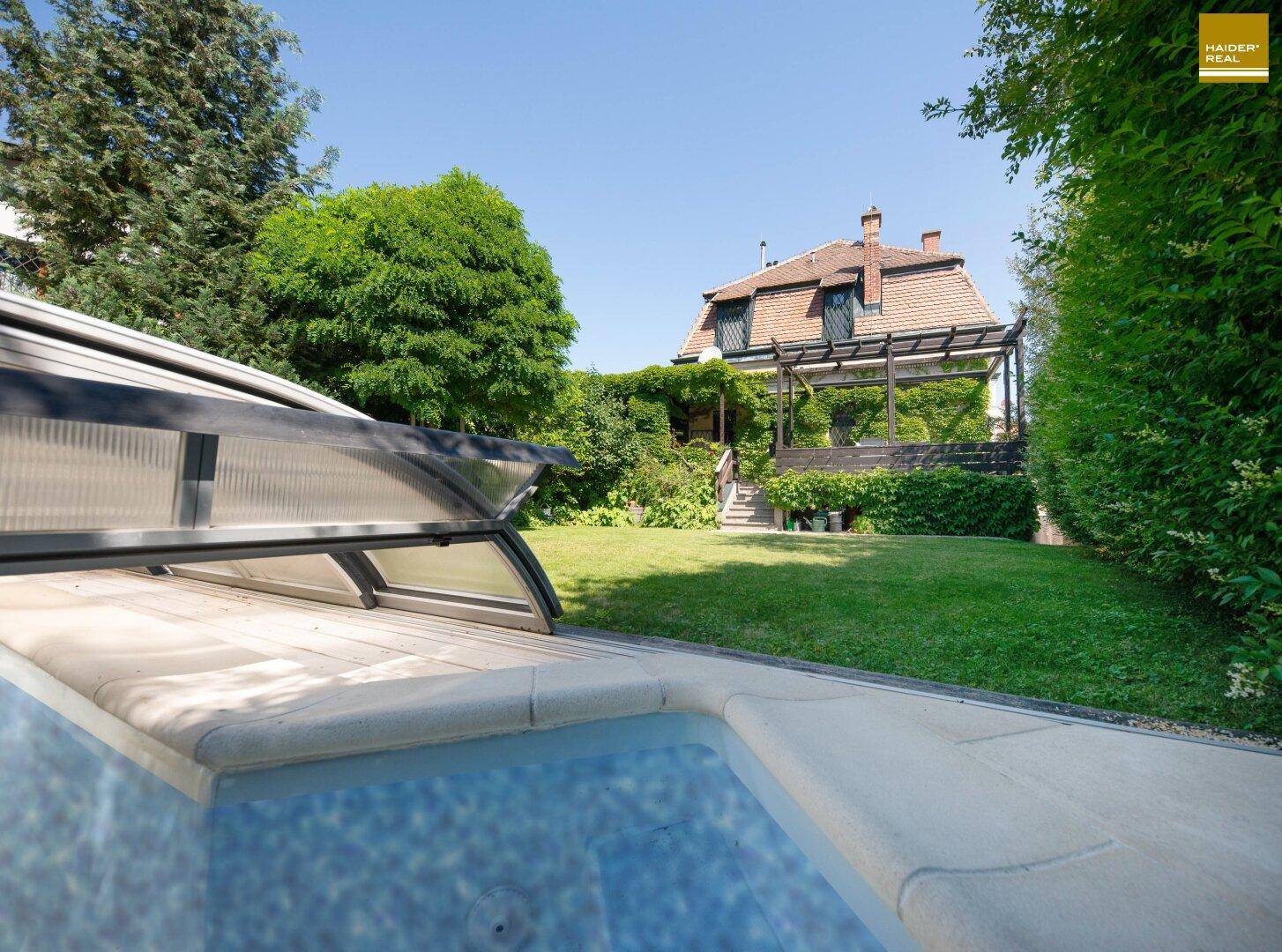 Garten mit Pool und Blick auf die historische Villa mit Pergola im Hintergrund.