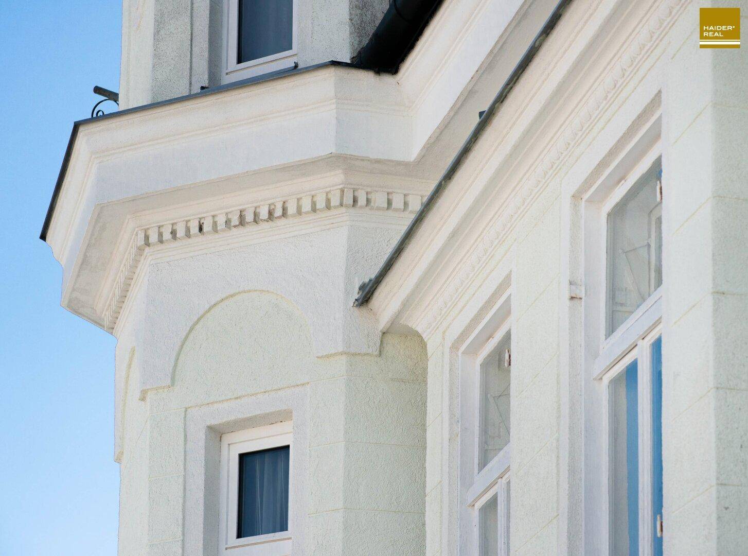 Architektonisches Detail der Fassade mit Stuckelementen und einem Erkerfenster.