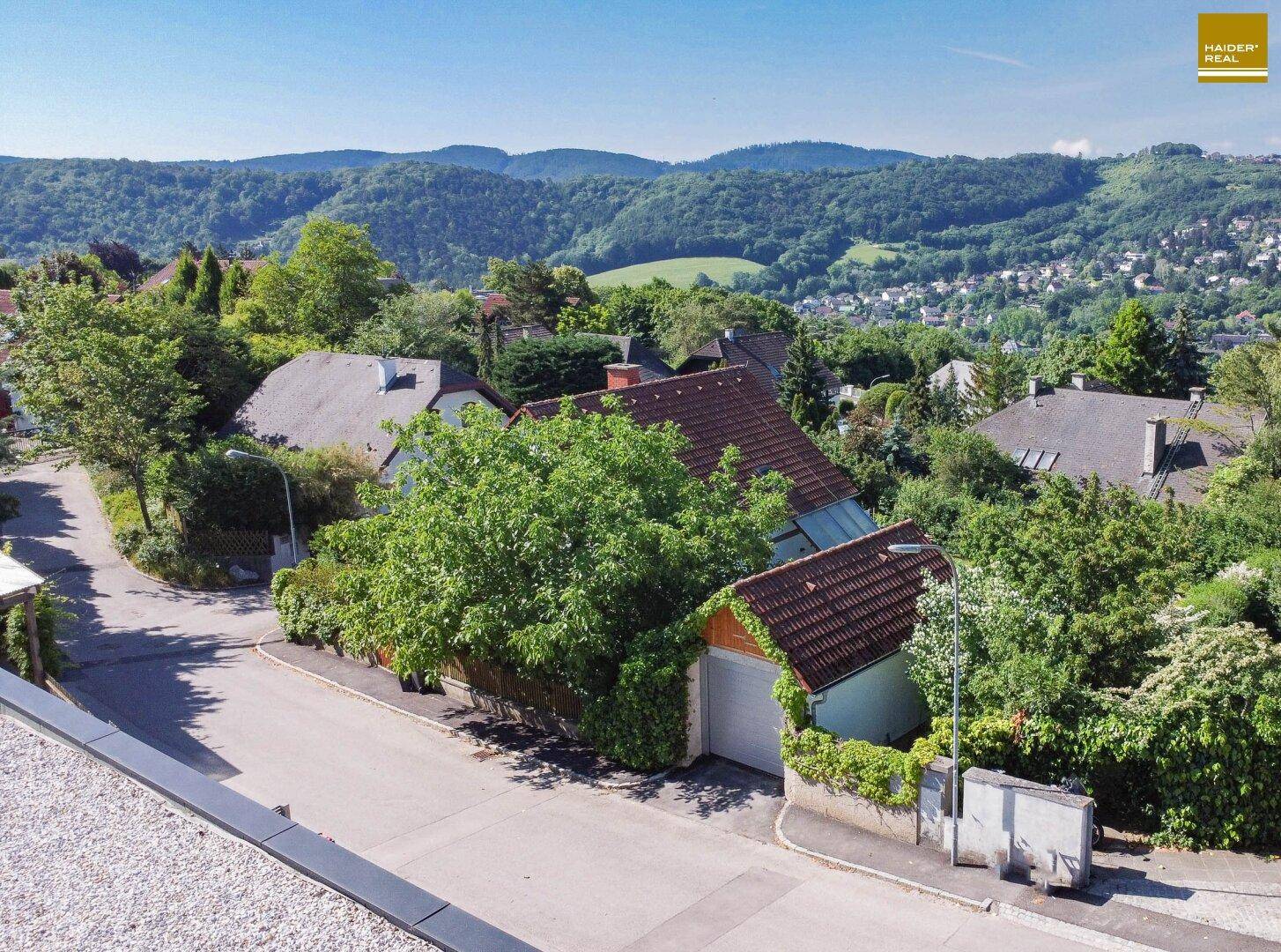 Weitläufiger Blick über die grüne Wohngegend mit vielen Bäumen und Häusern.