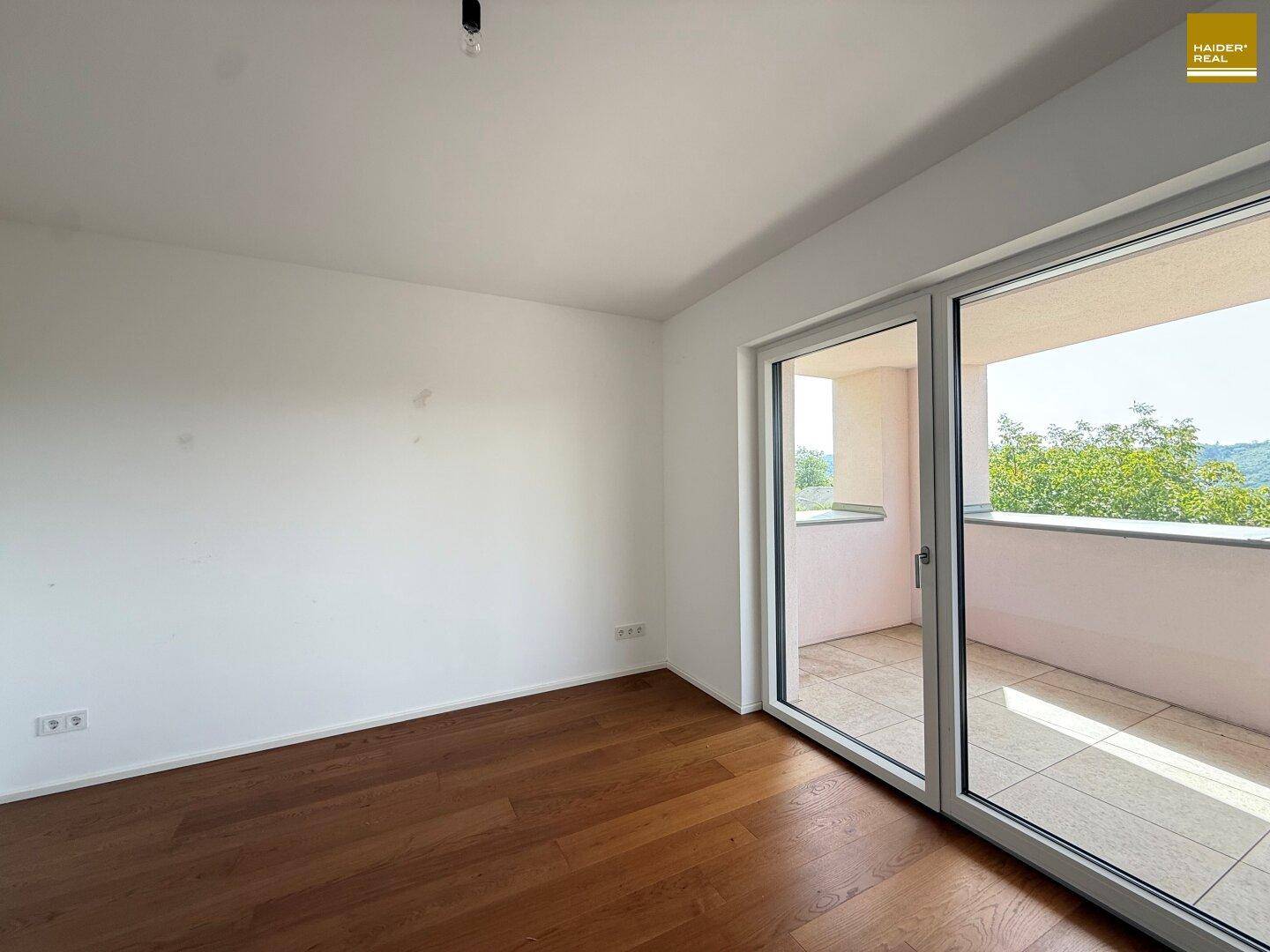 Helles Schlafzimmer mit Holzboden und direktem Zugang zu einem Balkon.