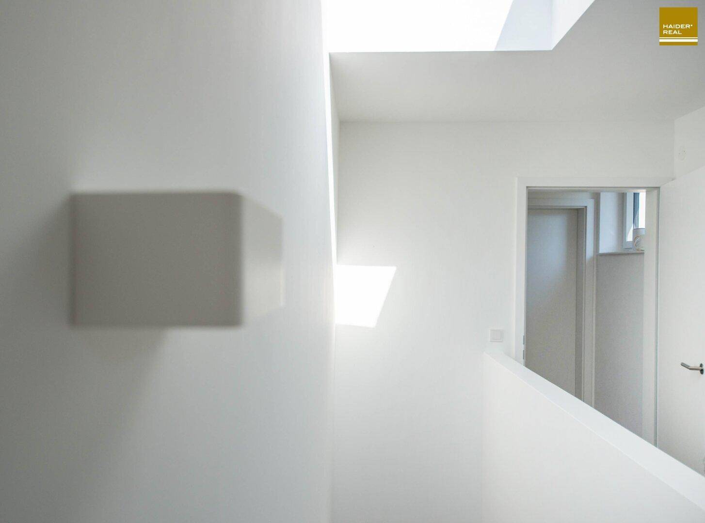 Heller Flur mit minimalistischem Design und natürlichem Lichteinfall durch Oberlichter.