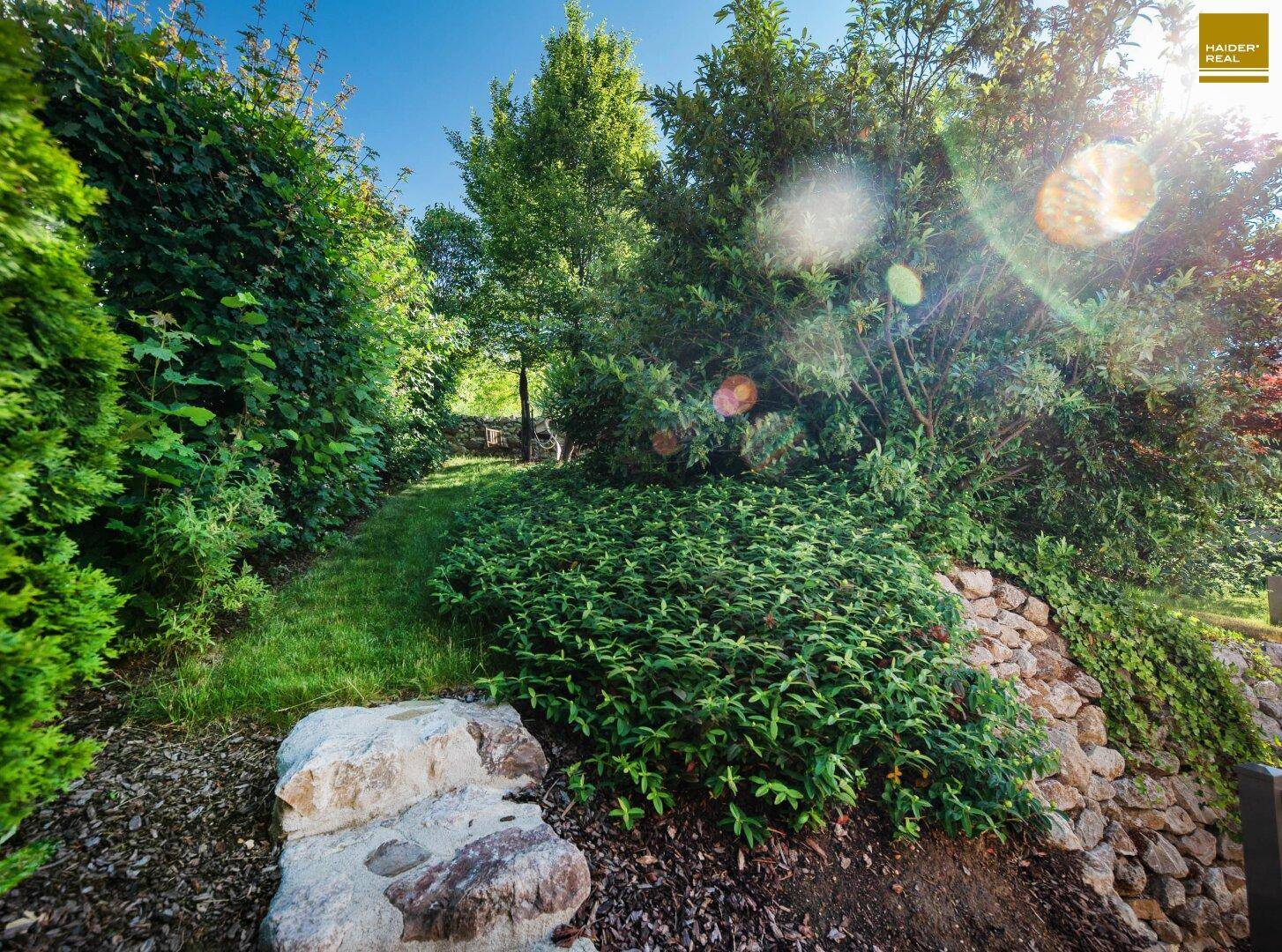 Idyllischer Gartenweg umgeben von üppigem Grün und Natursteinmauern.