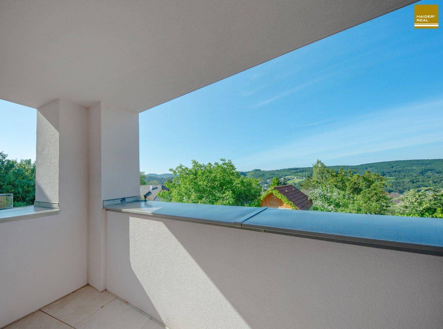 Heller Balkon mit weitem Blick über grüne Hügel und die umliegende Landschaft.