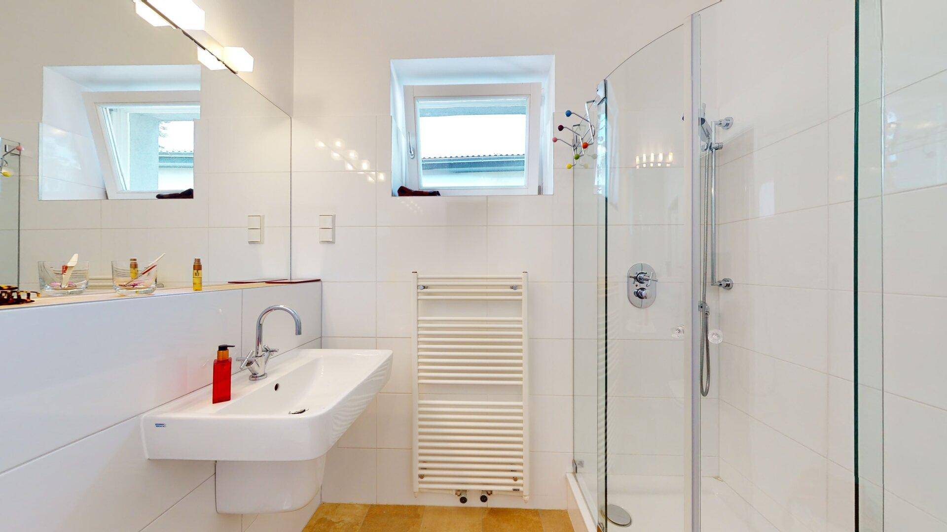 Modernes Badezimmer mit Duschkabine, Waschbecken und einem Fenster für Tageslicht.