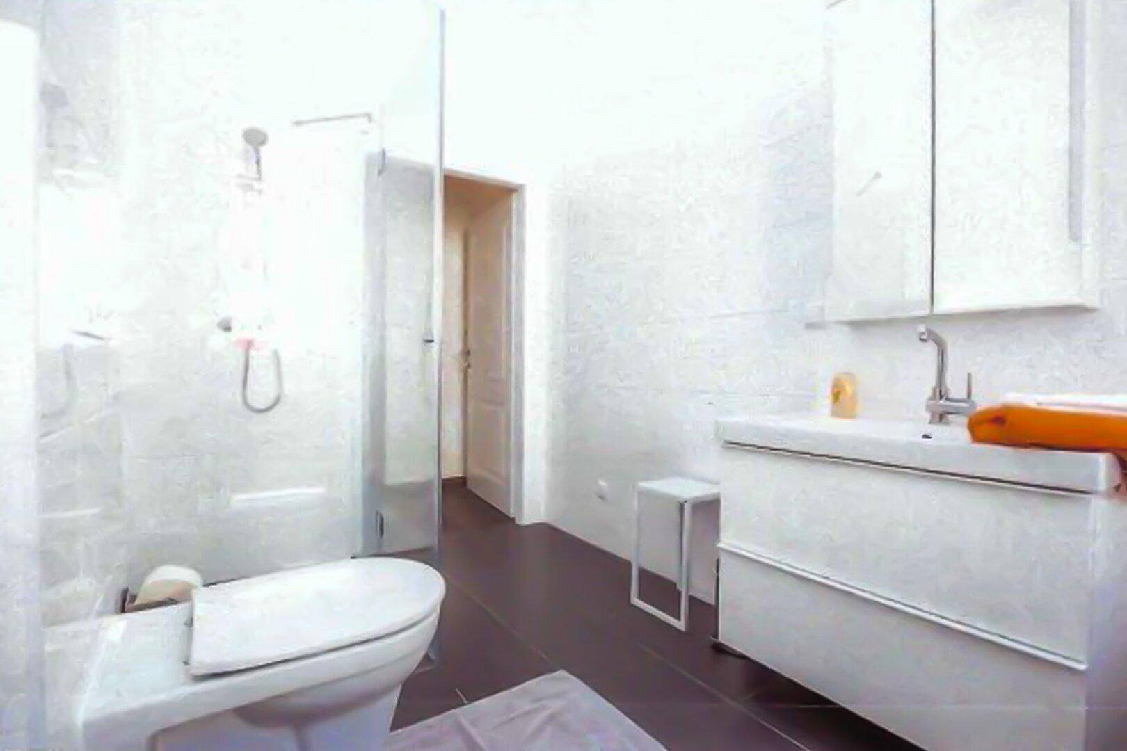 Modernes Badezimmer mit begehbarer Dusche, weißem Waschtisch und dunklen Bodenfliesen.