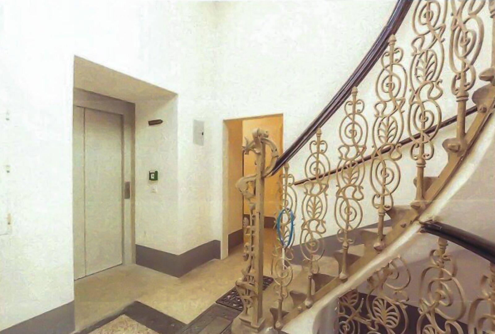 Heller Flur mit einer eleganten Treppe und einem modernen Aufzug für bequemen Zugang.