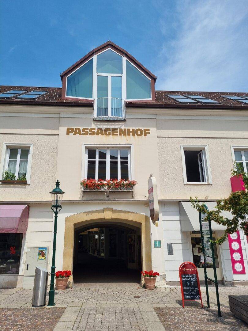 Historisches Gebäude "PASSAGENHOF" mit modernem Dachausbau und Balkon in der Stadt.
