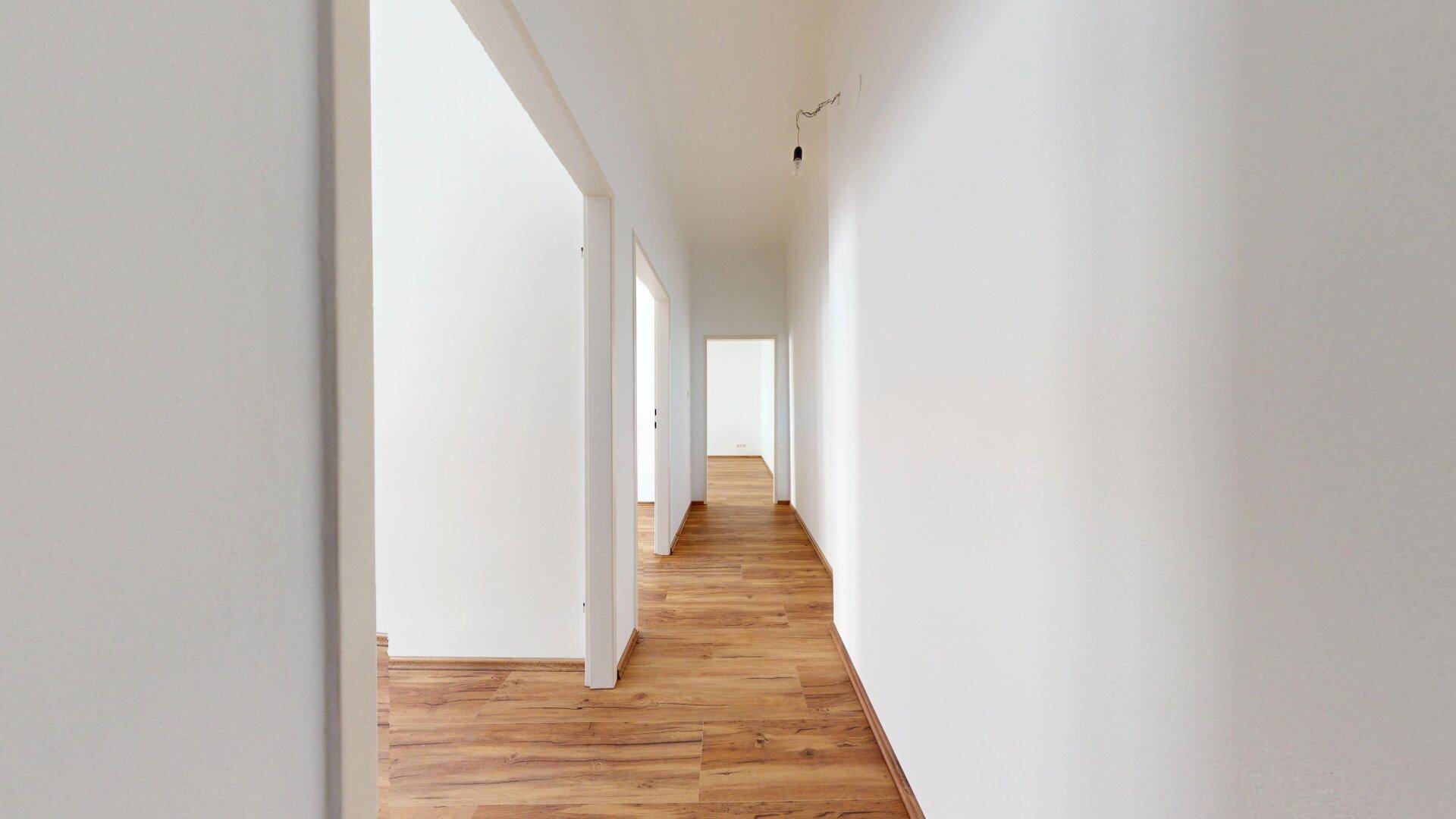 Langer, heller Flur mit Laminatboden und mehreren Türöffnungen, der die Räume verbindet.