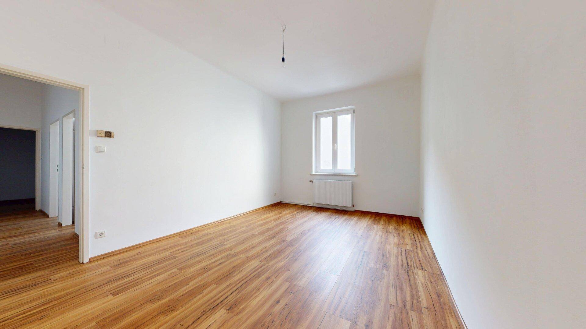 Geräumiger, heller Raum mit Laminatboden und Fenster, vielseitig nutzbar.