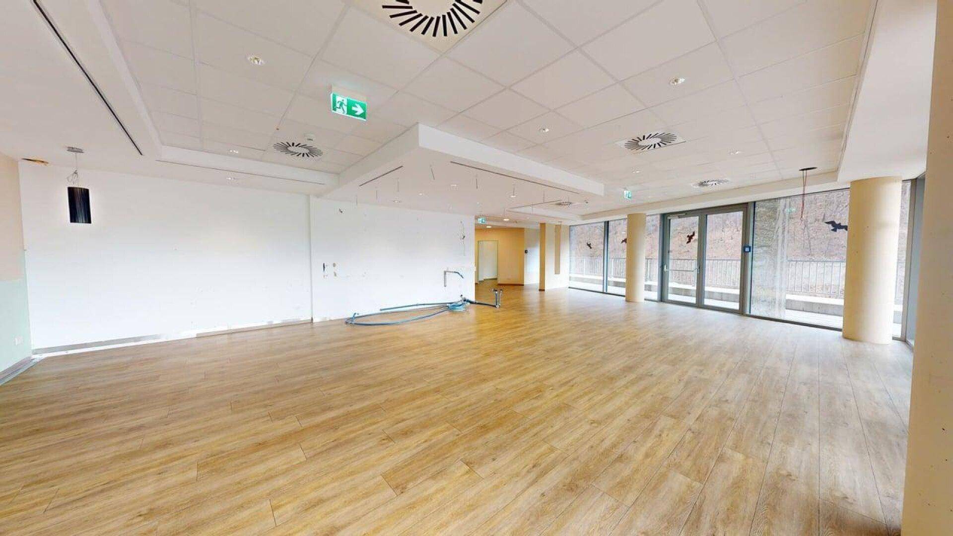 Weitläufiger Gewerberaum mit großen Fensterfronten und hellem Boden, ideal für verschiedene Nutzungskonzepte.