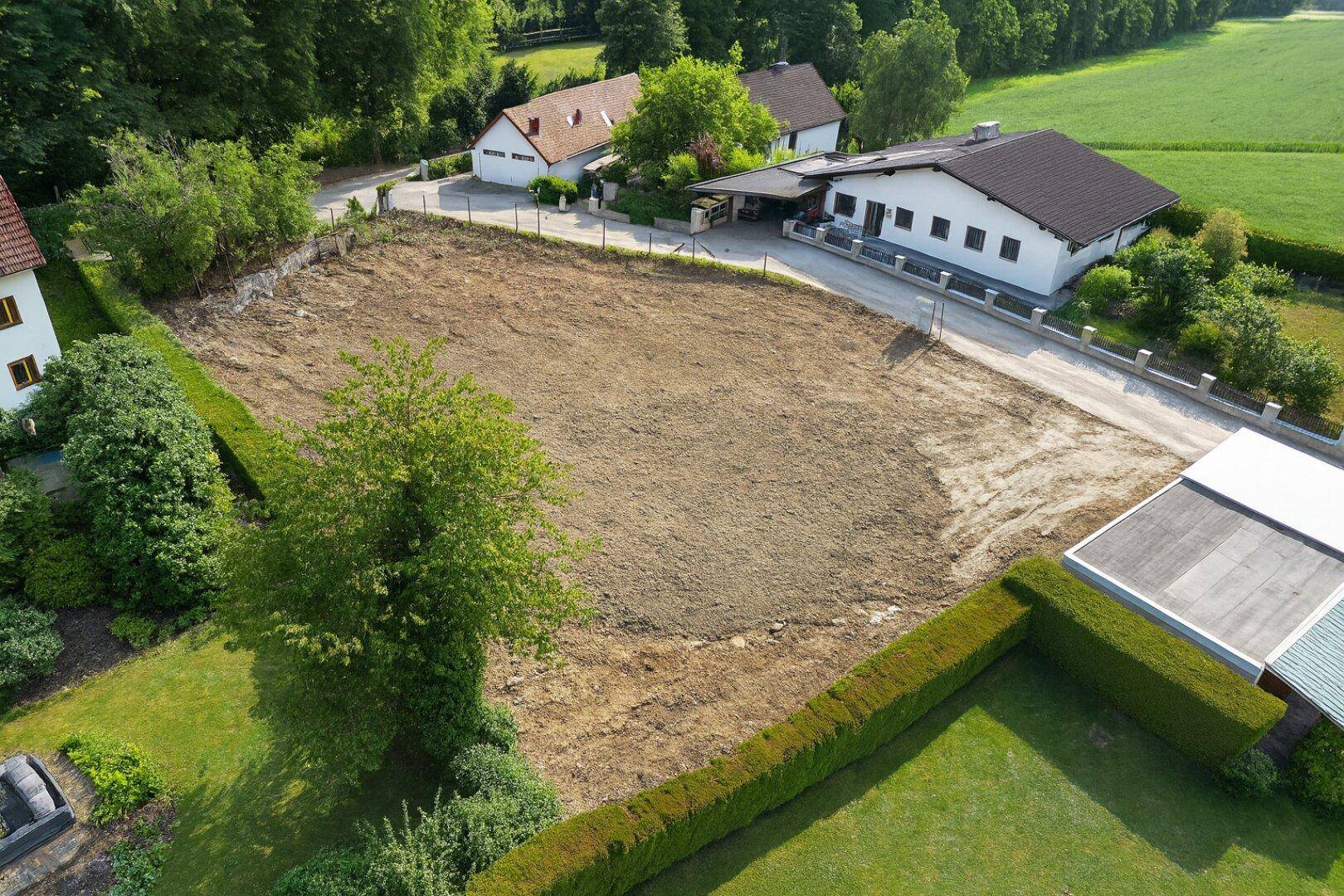 Luftaufnahme des Baugrundstücks mit umliegenden Häusern und Feldern in ländlicher Umgebung.
