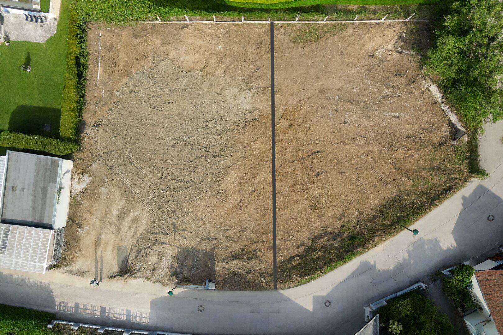 Nahaufnahme aus der Luft eines geräumten Baugrundstücks, bereit für die Bebauung, mit angrenzender Straße.