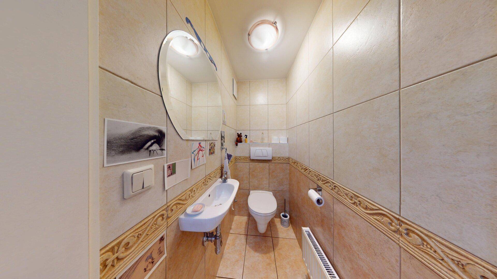 Kleines Gäste-WC mit beigefarbenen Fliesen, Wand-WC und Handwaschbecken.