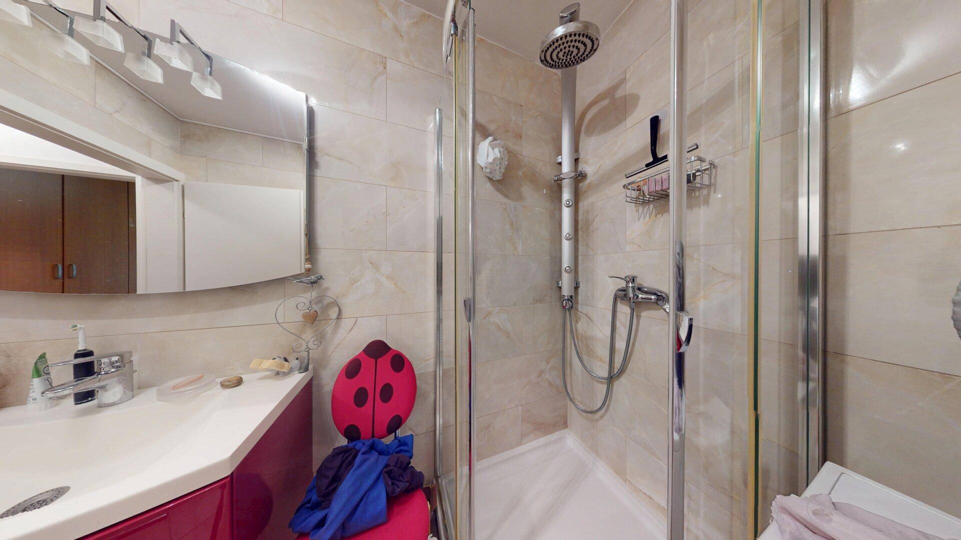 Duschbereich im Badezimmer mit Regendusche, Fliesen und moderner Duschkabine.