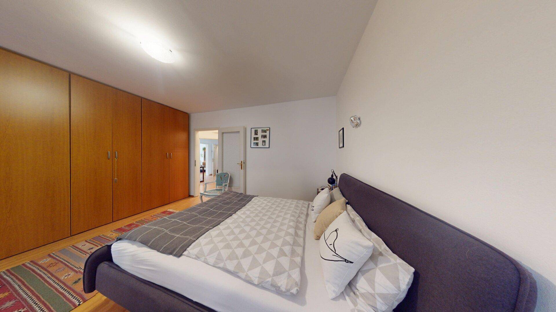 Geräumiges Schlafzimmer mit Einbauschränken, Doppelbett und Parkettboden.