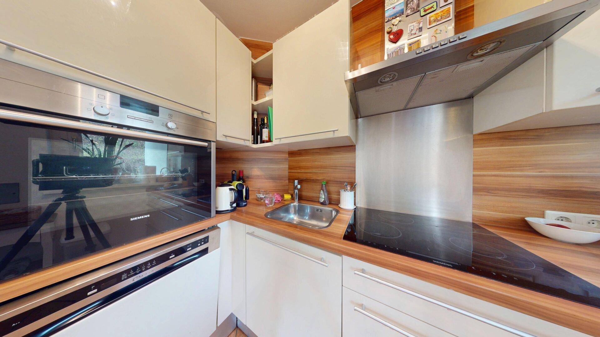 Moderne Küche mit Siemens-Geräten, Induktionskochfeld und Holz-Arbeitsplatte.