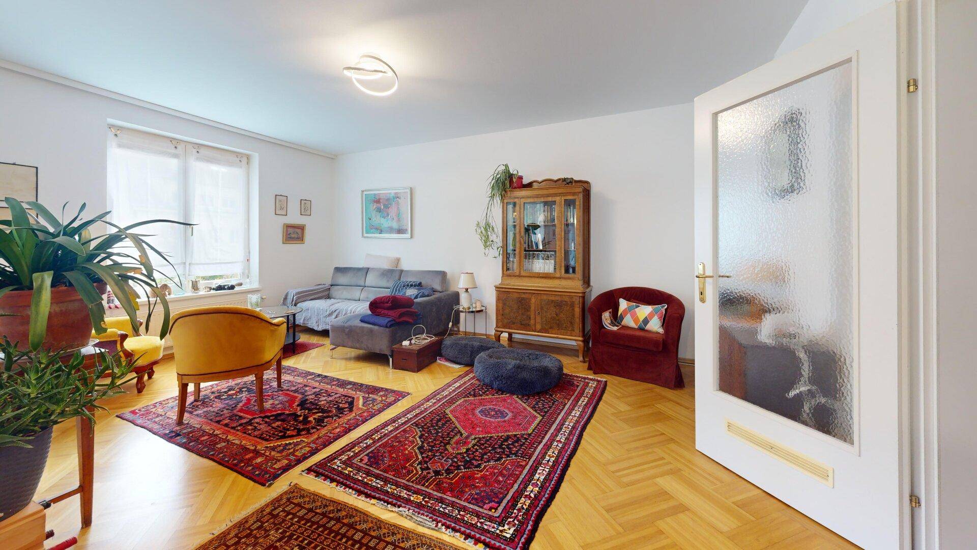 Helles Wohnzimmer mit Parkettboden, bequemen Sofas und traditionellen Teppichen.